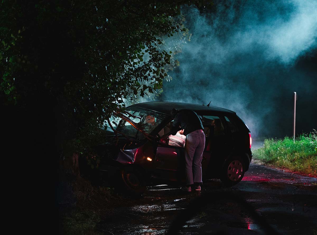 Nighttime car crash scene with a damaged vehicle