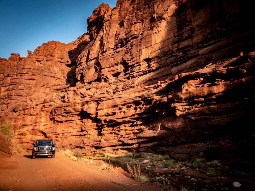 Pickup truck driving through a red rock canyon in Utah