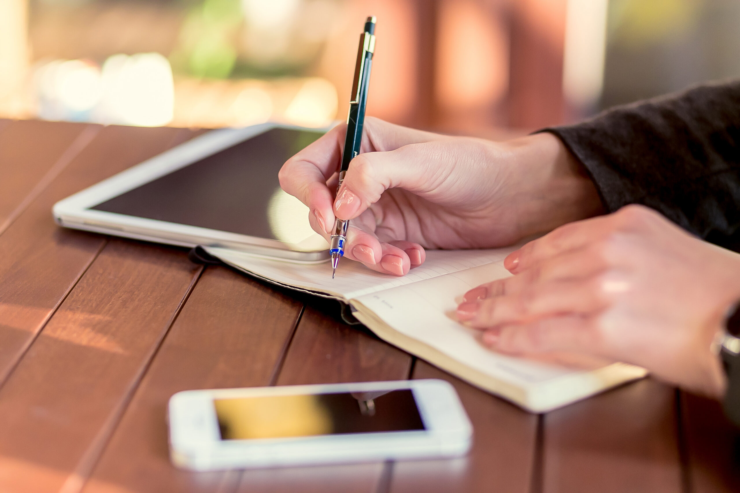 A close-up photograph of a person in Oregon keeping a handwritten symptom journal, documenting migraines and light sensitivity after a traumatic brain injury.