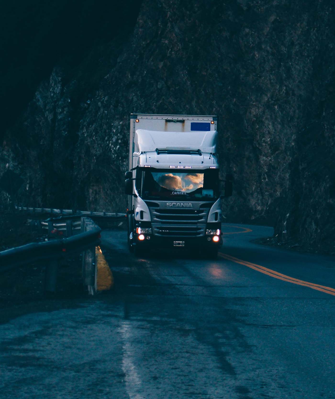 White commercial truck traveling on a wet mountain road