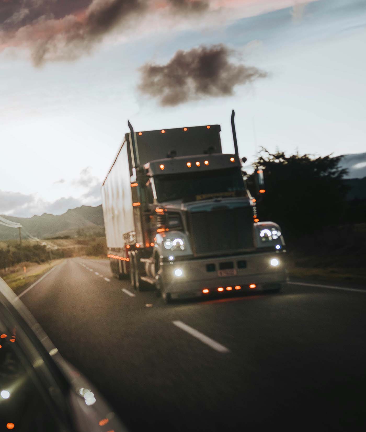 Semi-truck traveling on a highway at dusk